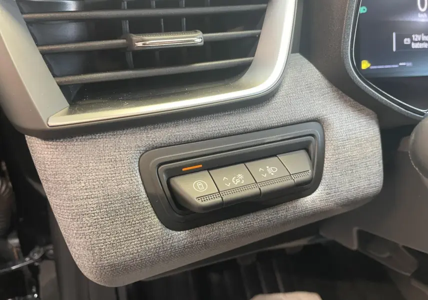 Détail des commandes d’éclairage et verrouillage sur la planche de bord tissu gris de la Renault Clio 2025.