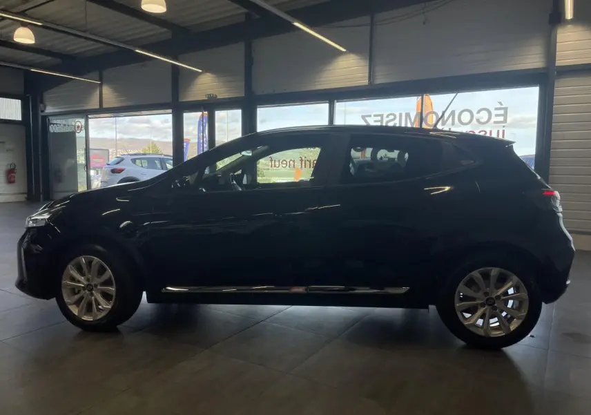Profil latéral droit d'une Renault Clio 1.5 Blue dCi 2025 en noir étoilé avec jantes alliage en intérieur showroom.