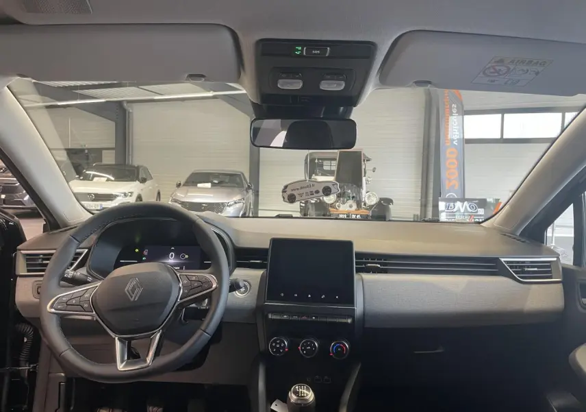 Vue intérieure avant de la Renault Clio 2025 avec volant multifonction, écran tactile 7 pouces et levier de vitesse manuel.