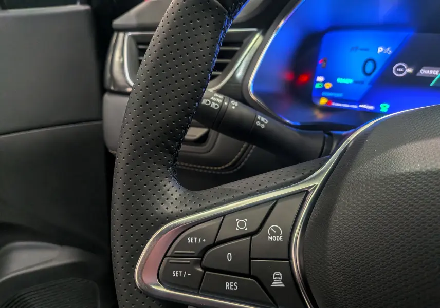 Gros plan sur le volant en cuir perforé et le tableau de bord numérique bleu du Renault Symbioz E-Tech hybride 2026.