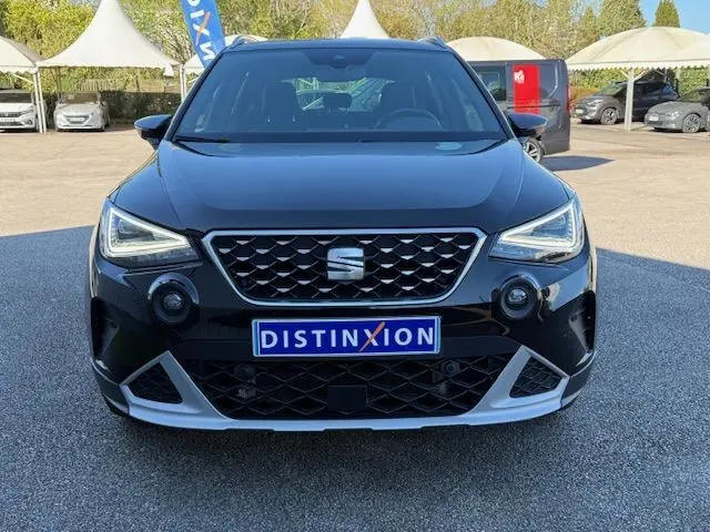 Vue frontale d'un SEAT Arona noir avec toit gris, calandre noire à motifs et projecteurs LED allumés.