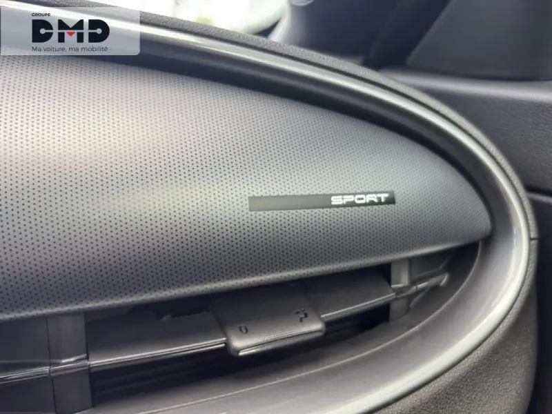 Détail intérieur du tableau de bord côté passager avec logo Sport sur finition noire texturée.