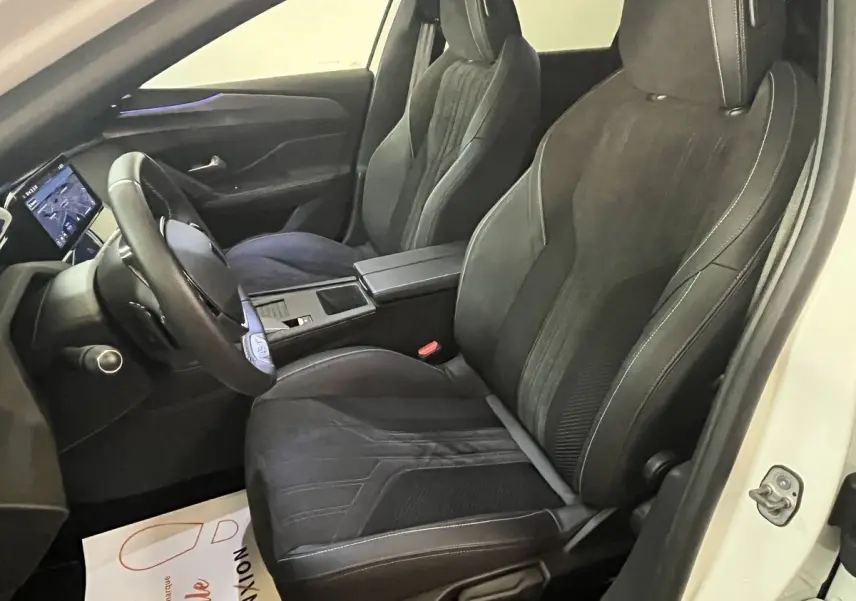 Vue intérieure côté conducteur de la Peugeot 308 GT PHEV 180 blanche avec sièges sport noirs et écran tactile.