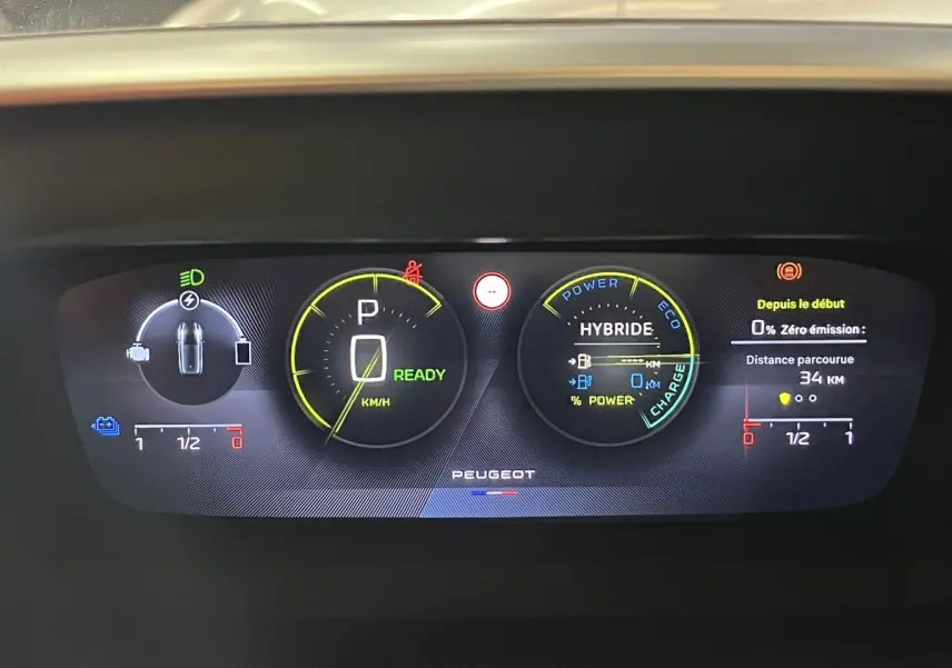Tableau de bord numérique de la Peugeot 308 GT PHEV blanc nacré, affichant l'état hybride et la vitesse à zéro.