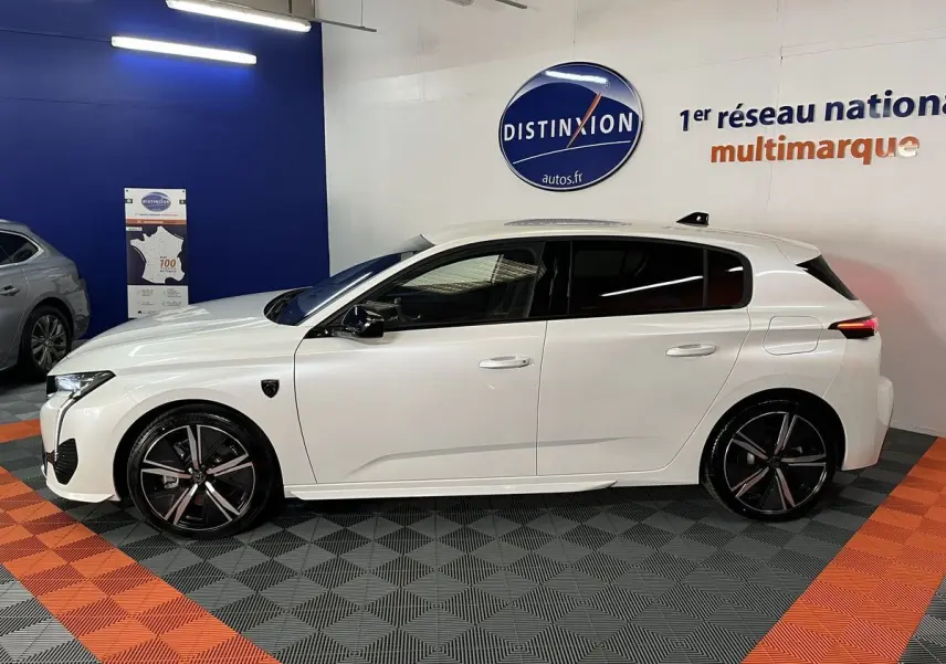 Profil côté gauche de la Peugeot 308 GT PHEV blanche nacrée en hybride rechargeable, avec jantes noires et détails sportifs visibles.