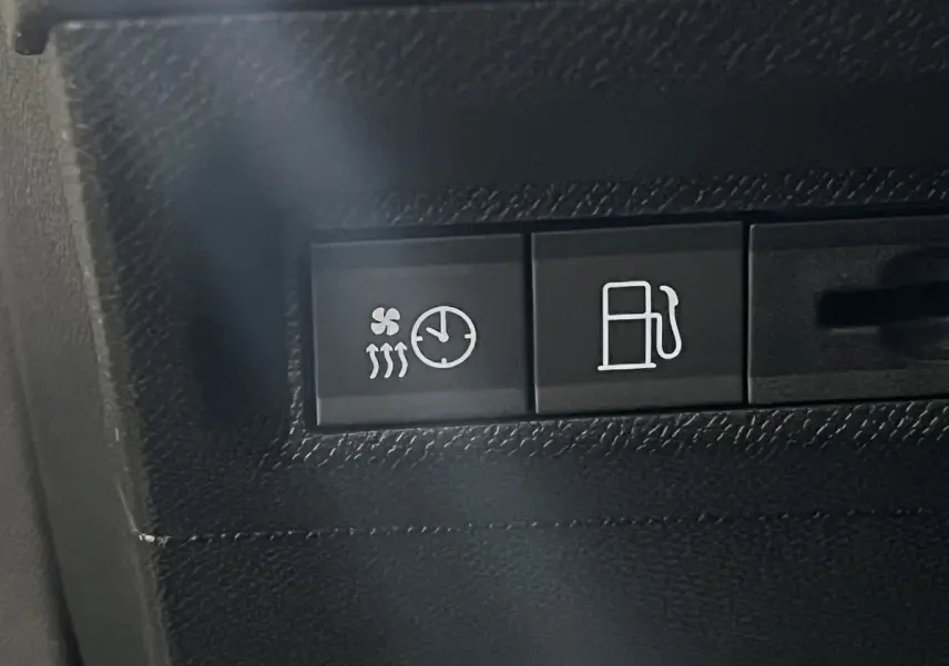 Gros plan sur les boutons de commande du chauffage et du carburant dans l'habitacle noir d'une Peugeot 308 GT PHEV blanc nacré.