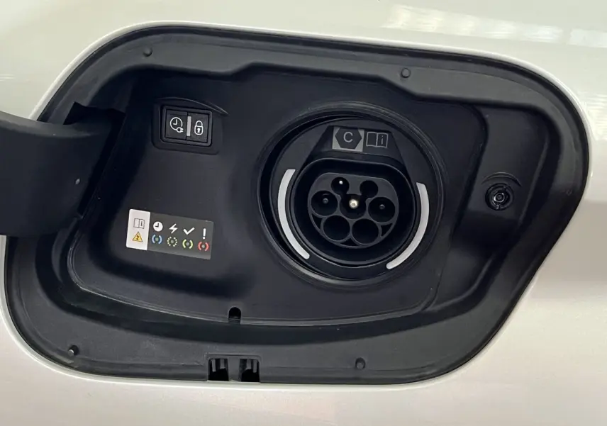 Prise de recharge hybride ouverte sur la carrosserie blanc nacré d'une Peugeot 308 GT PHEV 2022.