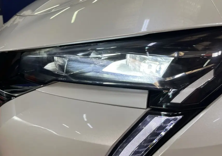 Gros plan sur le phare avant droit blanc nacré du Peugeot 308 GT PHEV 180 Hybride Rechargeable 2022 avec éclairage LED distinctif.