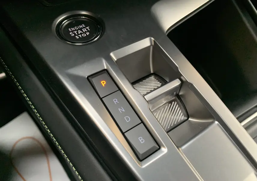 Gros plan sur la console centrale de la Peugeot 308 GT PHEV 180 blanche, avec boutons de boîte auto et bouton start/stop.