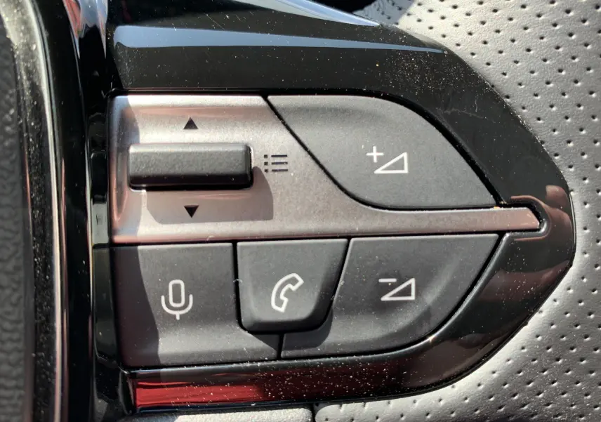 Gros plan sur les commandes vocales et téléphone du volant en cuir perforé du Peugeot 308 GT PHEV blanc nacré 2022.