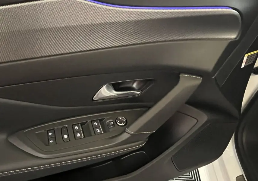 Détail de la porte côté conducteur de la Peugeot 308 GT PHEV 180 blanc nacré, avec commandes de vitres et poignée chromée.