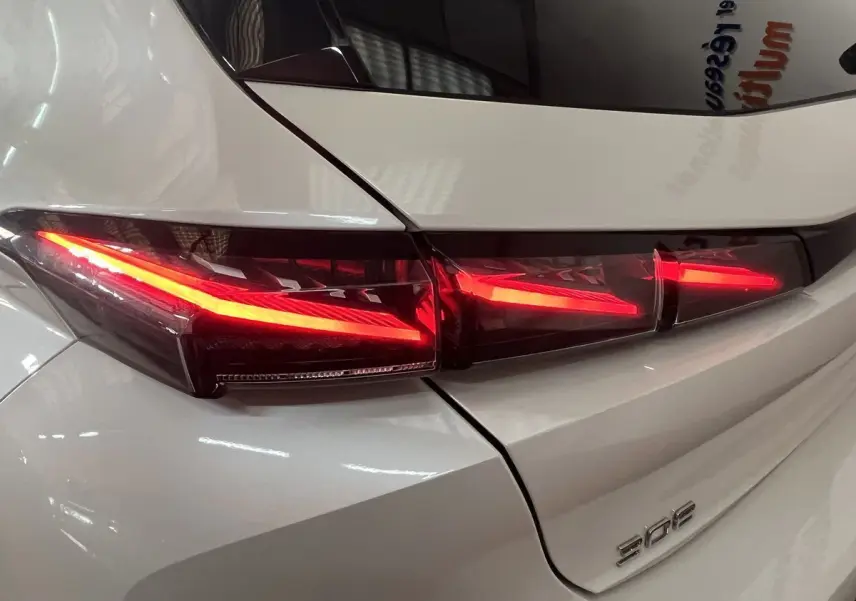 Gros plan sur le feu arrière droit allumé d’une Peugeot 308 GT PHEV blanc nacré, vue arrière détaillée.