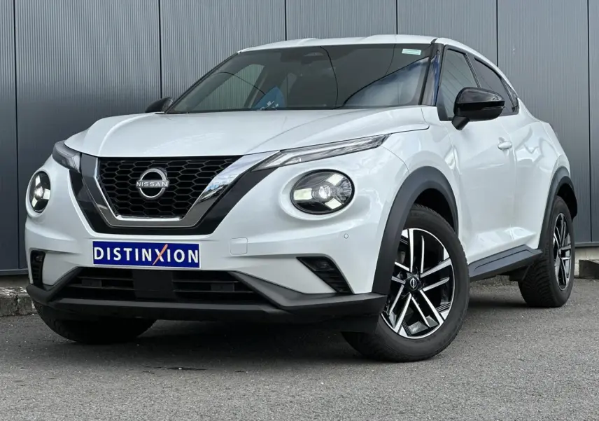 Nissan Juke blanc nacré en 3/4 avant droit, avec calandre chromée et jantes alliage noires et argentées.