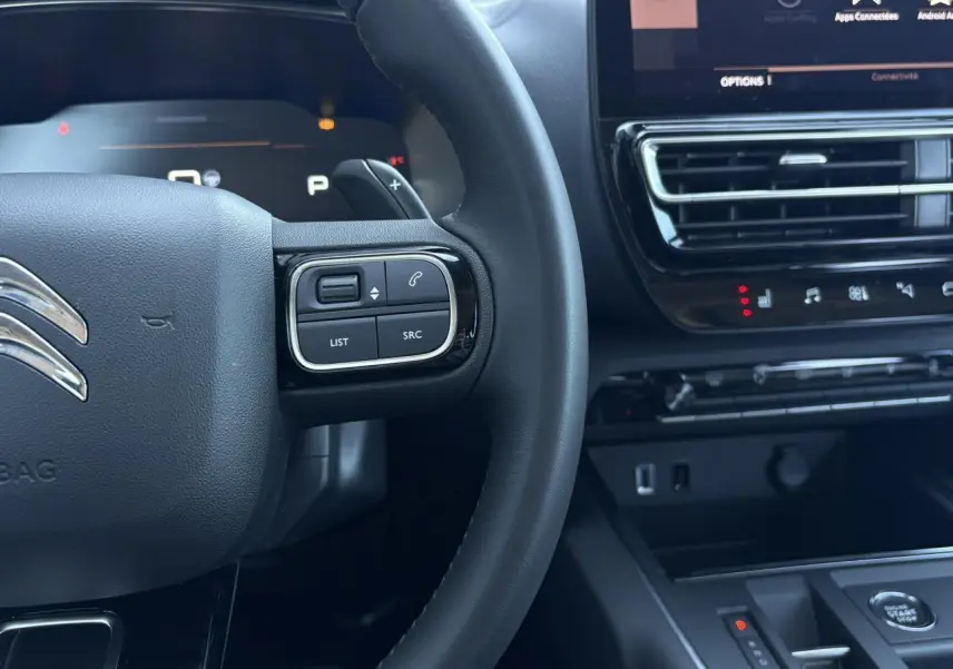 Gros plan sur le volant noir et la console centrale du Citroën C5 Aircross Hybrid 2025 avec commandes intégrées et écran tactile.