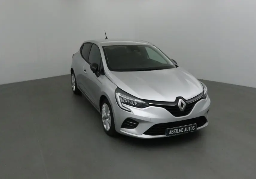 Renault Clio V gris platine vue 3/4 avant droit dans un studio, mettant en valeur ses optiques LED et calandre noire.