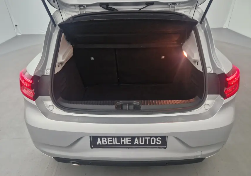 Coffre ouvert vu de l'arrière d'une Renault Clio V gris platine, montrant l'espace de chargement vide et l'éclairage intérieur.
