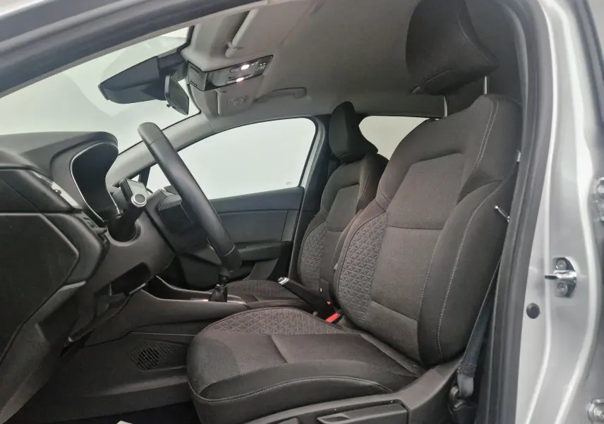 Intérieur avant droit de la Renault Clio V gris platine, sièges tissu noir avec motifs géométriques et volant visible.
