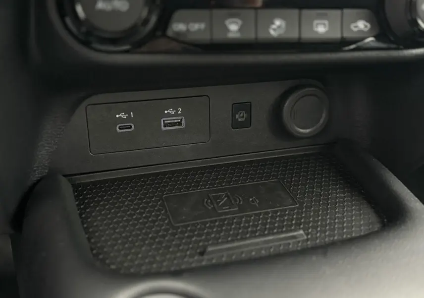 Gros plan sur la console centrale du Nissan Juke blanc nacré 2025, montrant ports USB et chargeur sans fil.