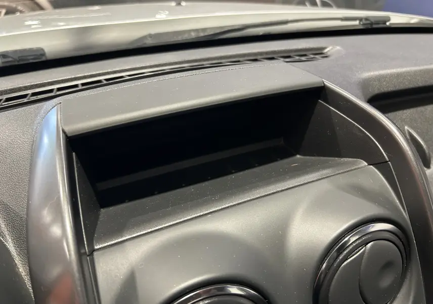 Détail du tableau de bord noir du Dacia Duster 2017, avec rangement ouvert et aérateurs ronds visibles.