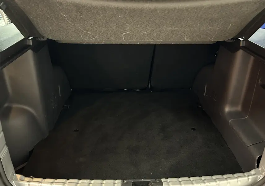 Coffre ouvert du Dacia Duster gris 2017, montrant l'espace de chargement vide et la moquette noire.