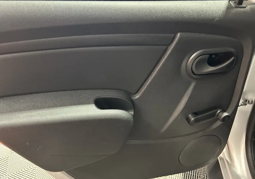 Gros plan sur la porte intérieure côté droit du Dacia Duster gris 2017, avec poignée et manivelle de vitre manuelle.