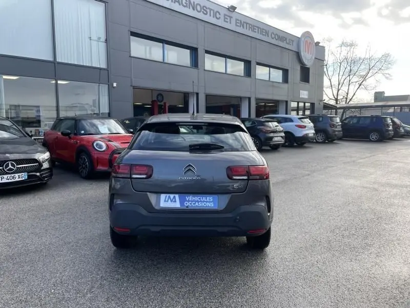 Vue arrière d'une Citroën C4 Cactus gris foncé métal 2019, version HDI 100 Feel, stationnée devant un garage.