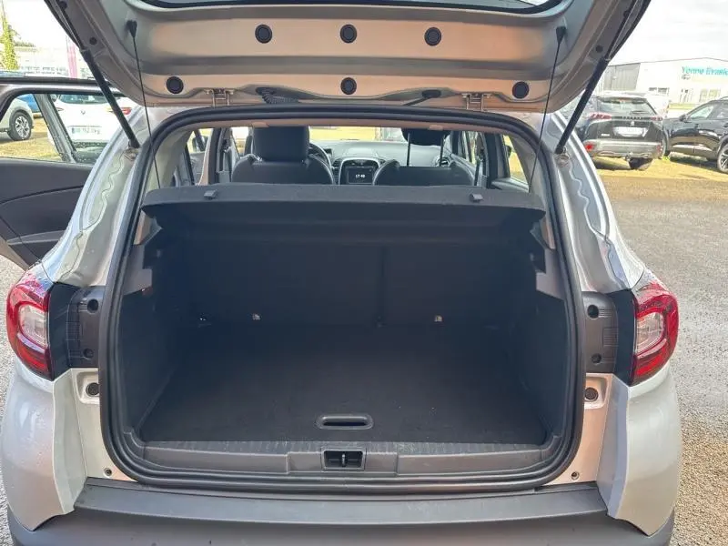 Coffre ouvert vu de l'arrière d'un Renault Captur gris platine 2019, intérieur sombre et banquette arrière visible.