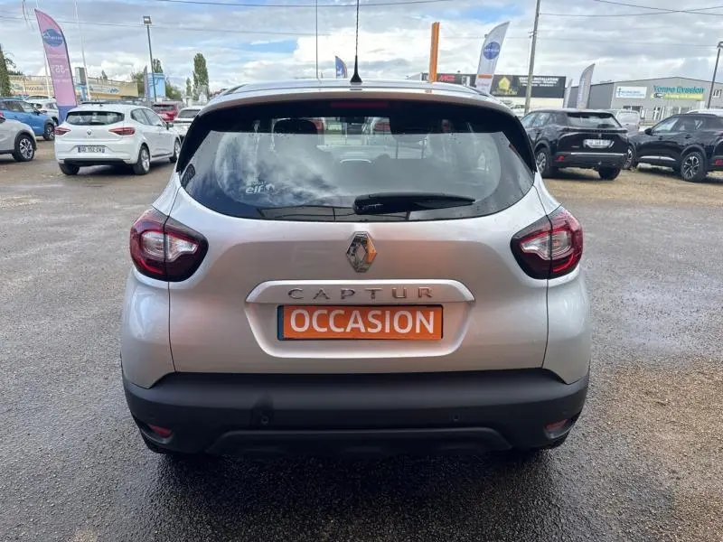 Vue arrière d'un Renault Captur gris platine avec plaque "OCCASION" sur un parking extérieur.