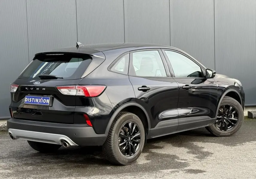 Vue 3/4 arrière droite d'un Ford Kuga 2024 noir Obsidien avec jantes alliage noires et double sortie d'échappement.
