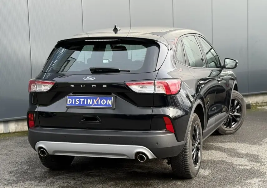 Vue 3/4 arrière droite d'un Ford Kuga noir Obsidien avec jantes alliage noires et double sortie d'échappement.