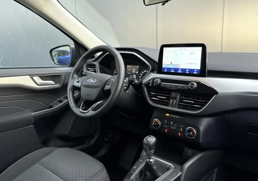 Vue intérieure côté conducteur du Ford Kuga 2024 noir Obsidien, avec tableau de bord moderne et écran tactile GPS.