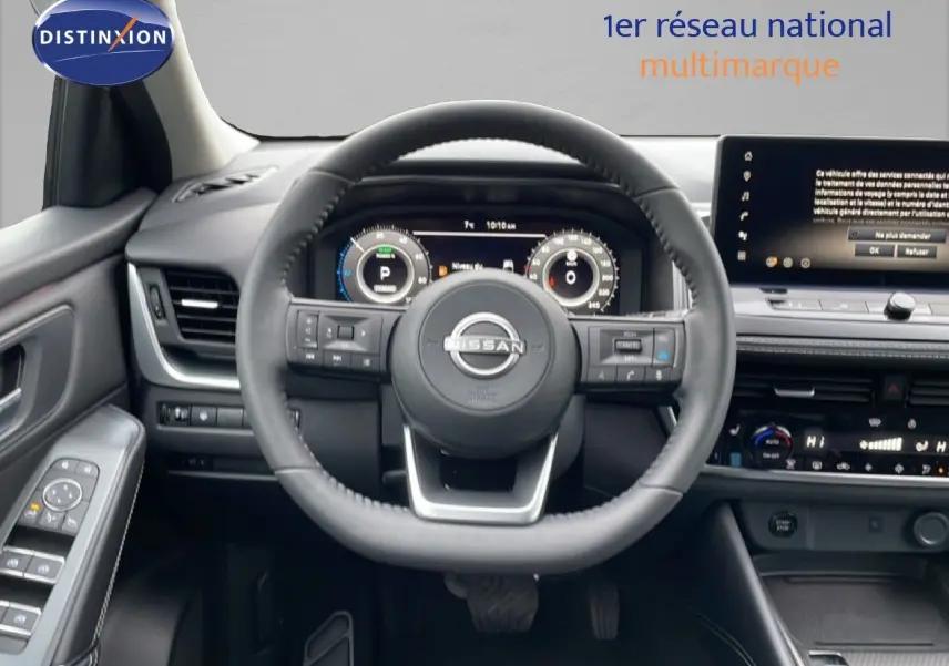 Vue intérieure centrée sur le volant du Nissan Qashqai blanc nacré 2025 avec tableau de bord digital et écran tactile.