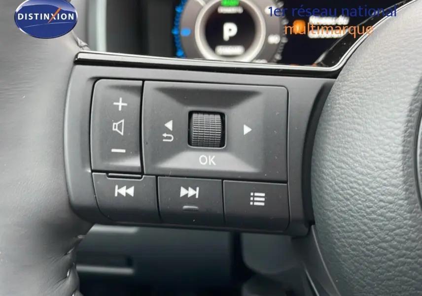 Gros plan sur les commandes au volant côté gauche du Nissan Qashqai blanc nacré 2025, affichage numérique en arrière-plan.