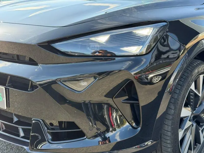 Gros plan sur l'avant droit du CUPRA Formentor noir Minuit métallisé, mettant en valeur le phare LED et la calandre sportive.