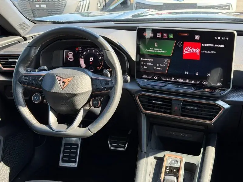 Vue intérieure du tableau de bord et volant du CUPRA Formentor 1.5 eTSI Hybrid noir Minuit, avec écran tactile central allumé.
