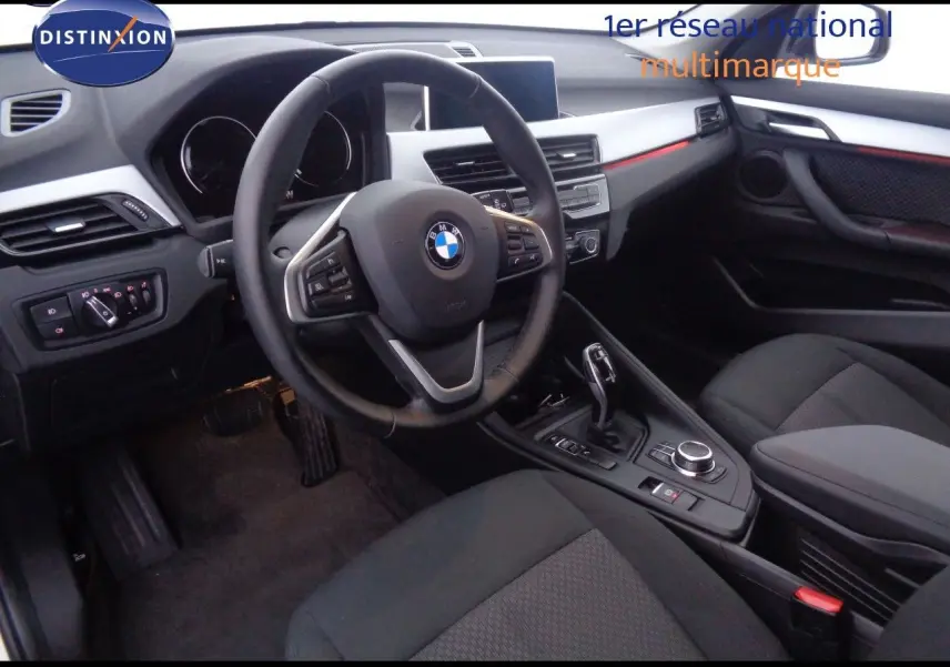 Intérieur avant droit d'une BMW X1 2022 avec volant multifonction, sellerie noire et console centrale moderne.