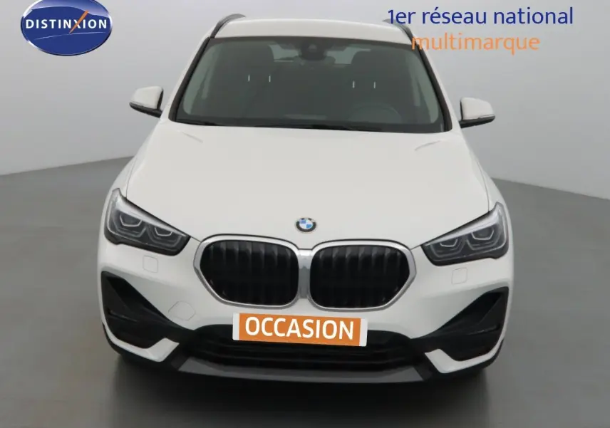Vue frontale d'un BMW X1 blanc Alpine Metal avec calandre noire et phares LED marqués dans un studio.