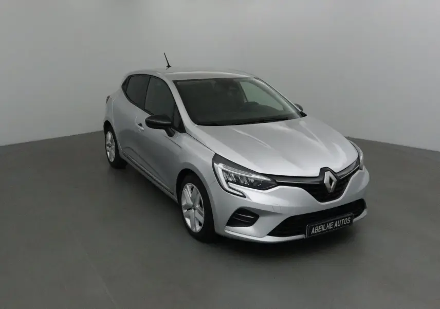 Renault Clio V gris platine vue 3/4 avant droit dans un studio, avec calandre noire et phares LED marqués.