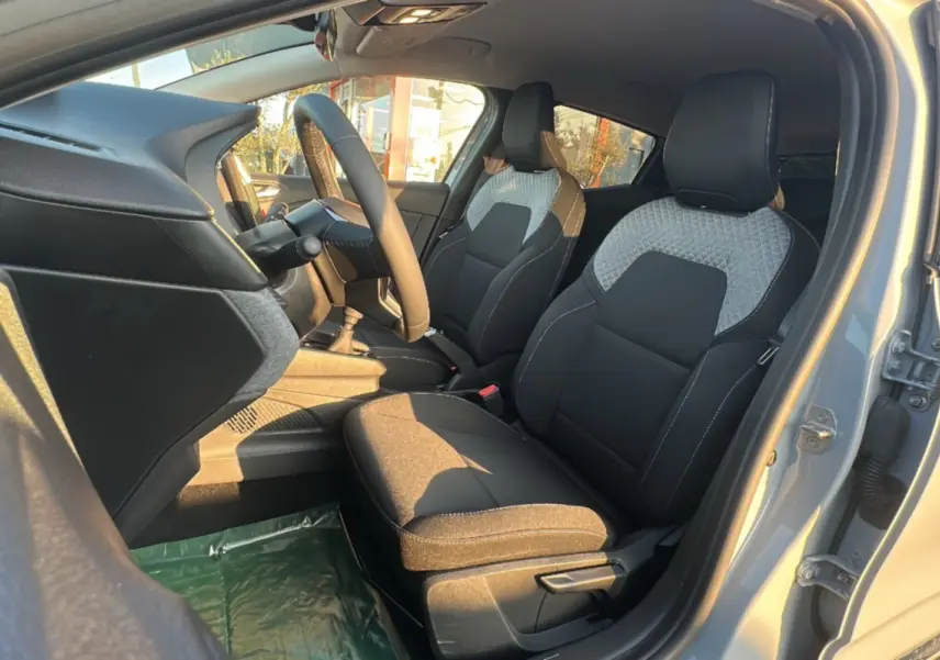 Vue intérieure côté conducteur de la Renault Clio DCI 100 Evolution Camera 2025 en gris rafale, sièges tissu noir et gris.