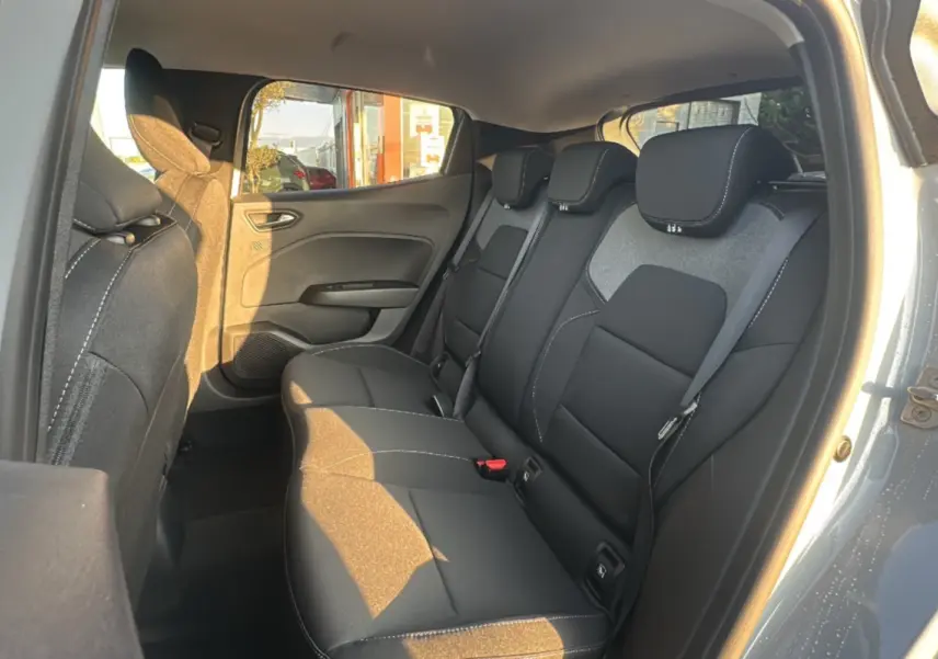 Vue intérieure arrière droite de la Renault Clio 2025 gris rafale, montrant les sièges arrière en tissu noir avec surpiqûres blanches.