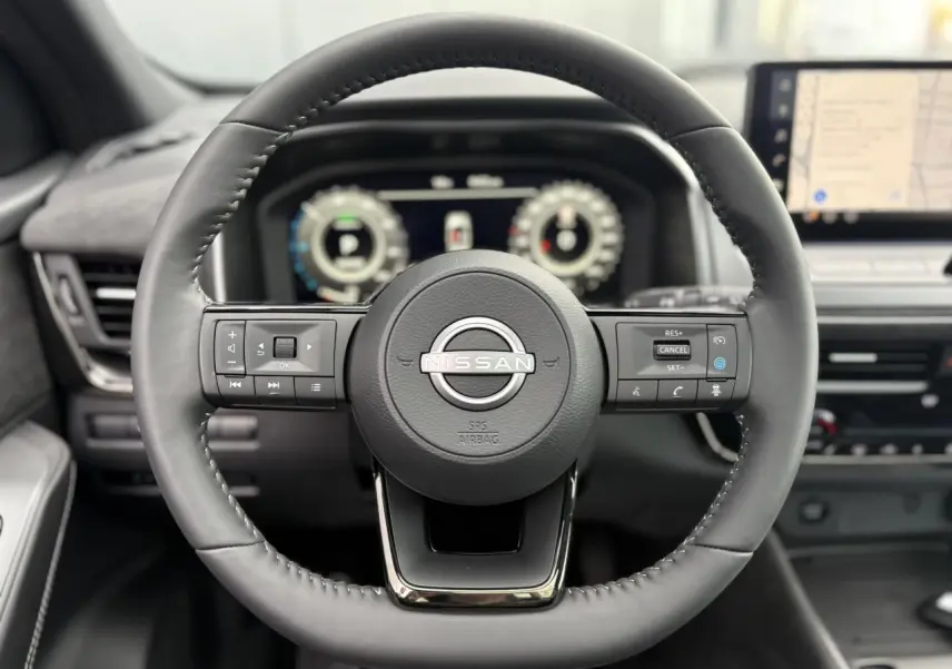 Volant cuir noir de Nissan Qashqai 2025 avec commandes intégrées, tableau de bord numérique et écran tactile GPS visible.