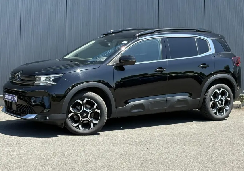 Vue de profil côté gauche d'un Citroën C5 Aircross Hybrid 2025 noir Perla avec jantes alliage et barres de toit noires.