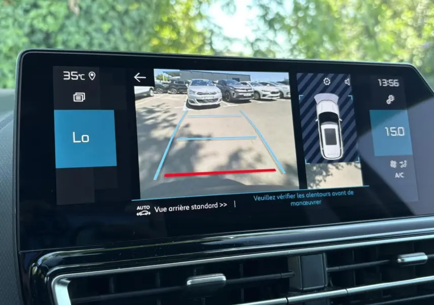Écran tactile intérieur montrant la caméra de recul avec vue arrière d’un parking ensoleillé.