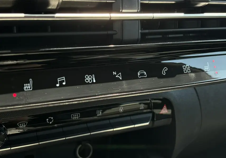 Gros plan sur la console centrale noire brillante du Citroën C5 Aircross Hybrid 2025 avec commandes tactiles et voyants rouges allumés.