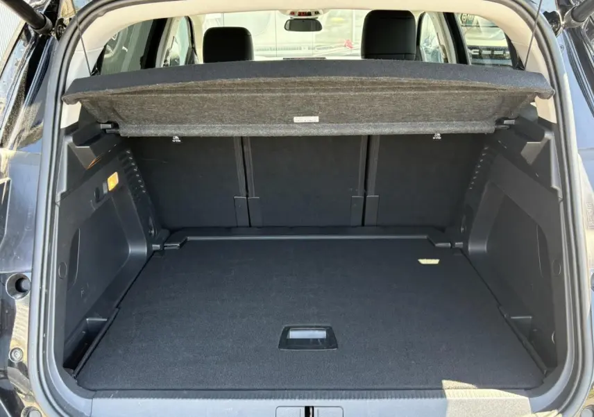 Coffre ouvert vu de l'arrière d'un Citroën C5 Aircross Hybrid 2025 noir Perla avec cache-bagages relevé.