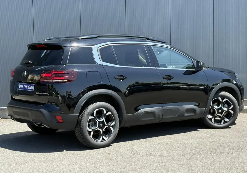 Vue 3/4 arrière droite du Citroën C5 Aircross Hybrid noir Perla avec jantes diamantées et barres de toit noires.