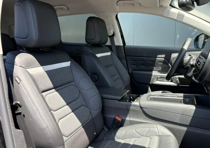 Vue intérieure côté droit des sièges avant en tissu et cuir noir du Citroën C5 Aircross Hybrid 2025 avec accoudoir central.