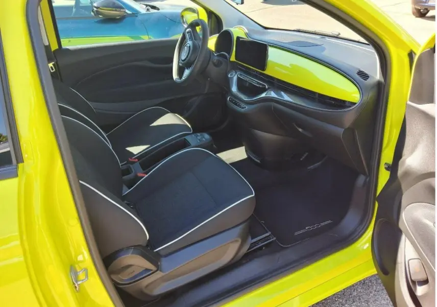 Intérieur côté conducteur d'une FIAT 500 électrique 2024 jaune Acid, avec tableau de bord et sellerie noire contrastée.