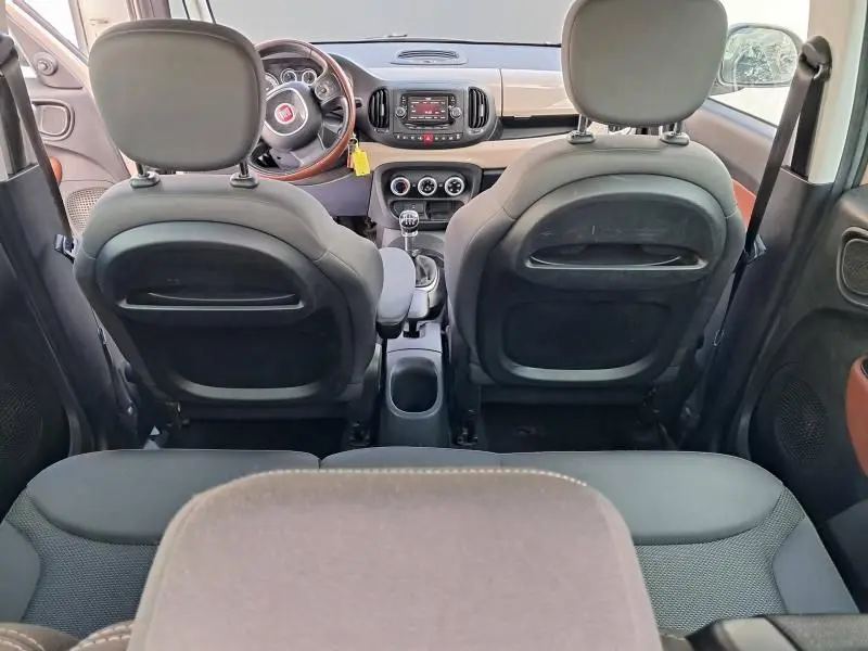 Vue intérieure arrière de la Fiat 500L beige 2014, montrant le tableau de bord, volant bois et levier de vitesse manuel.