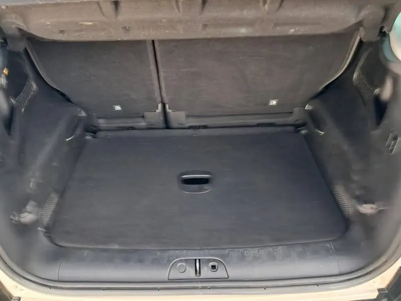 Coffre ouvert vu de l'arrière d'une FIAT 500L beige 2014, montrant l'espace de chargement vide et le revêtement noir.